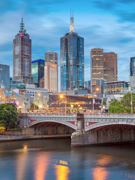 Melbourne city skyline with Yarra River and bridge at dusk.