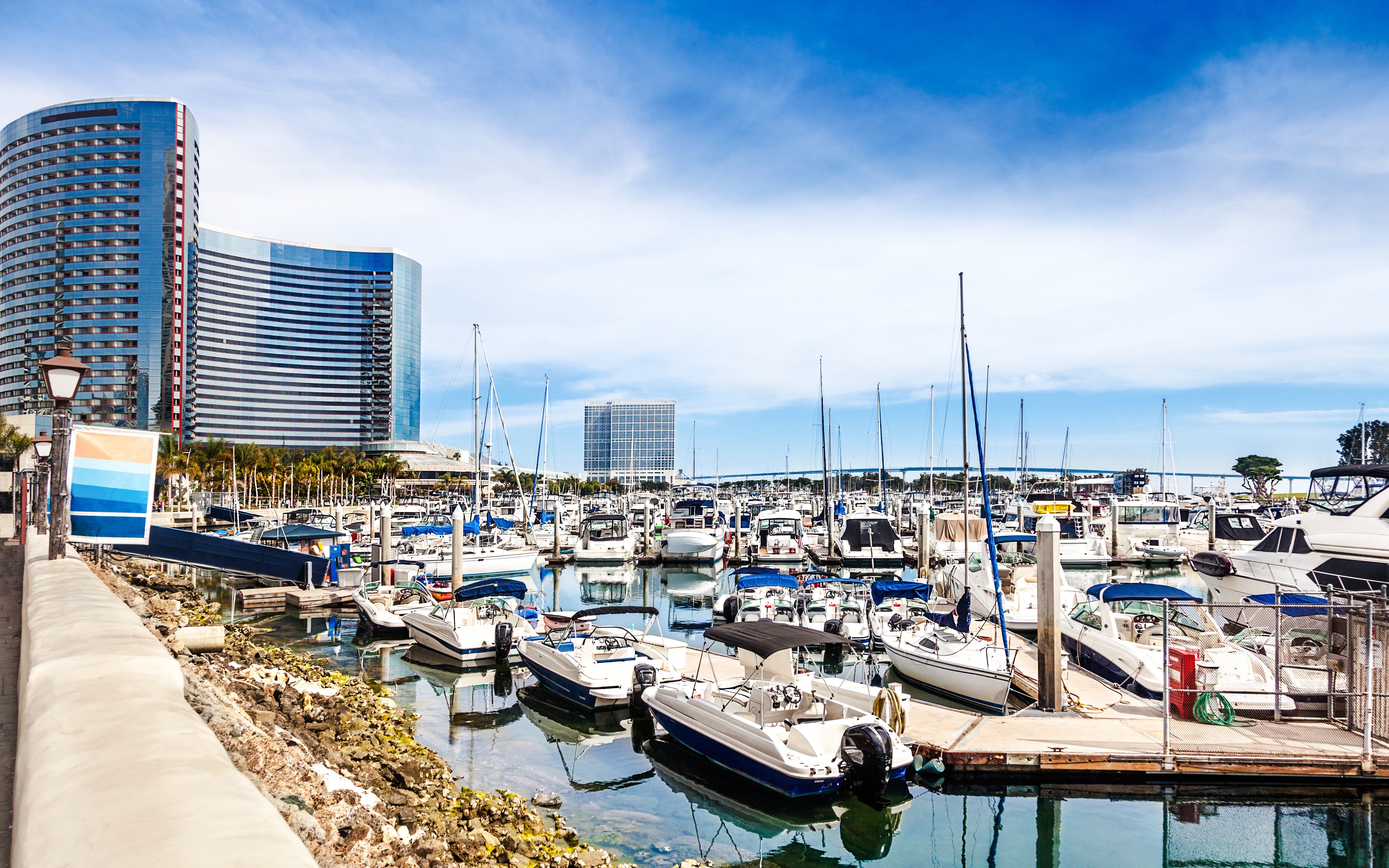Boats docked at San Diego's Embarcadero Marina with modern buildings in the background.
