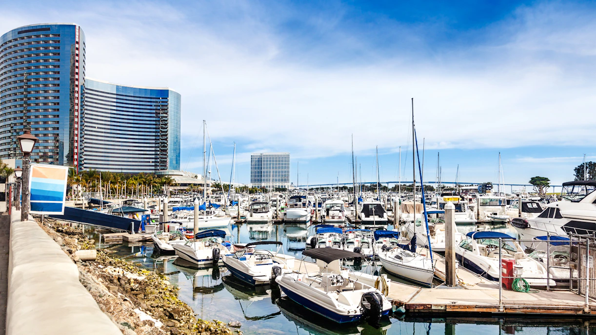 Boats docked at San Diego's Embarcadero Marina with modern buildings in the background.