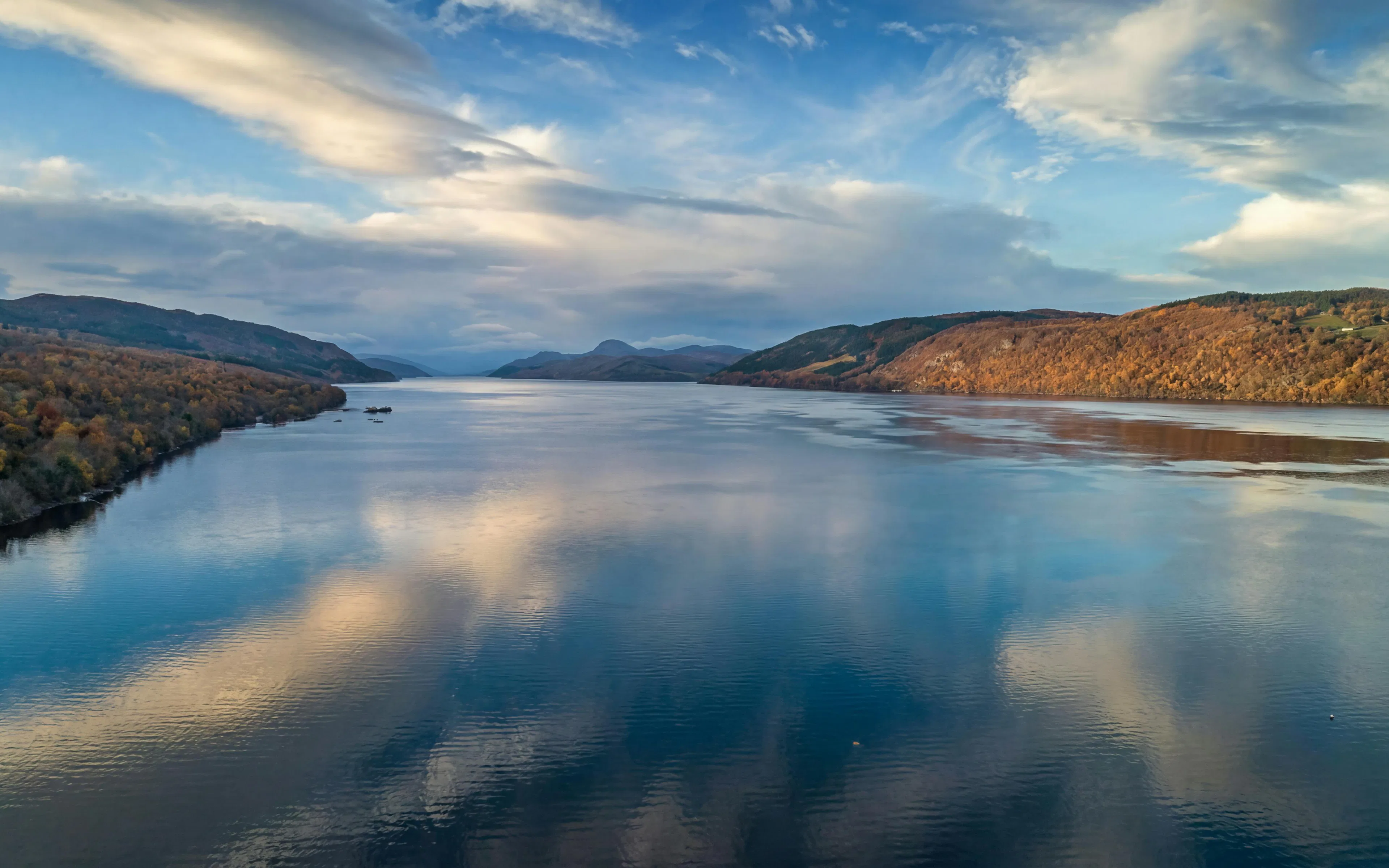 Loch Ness with surrounding hills and cloudy sky in Scotland.