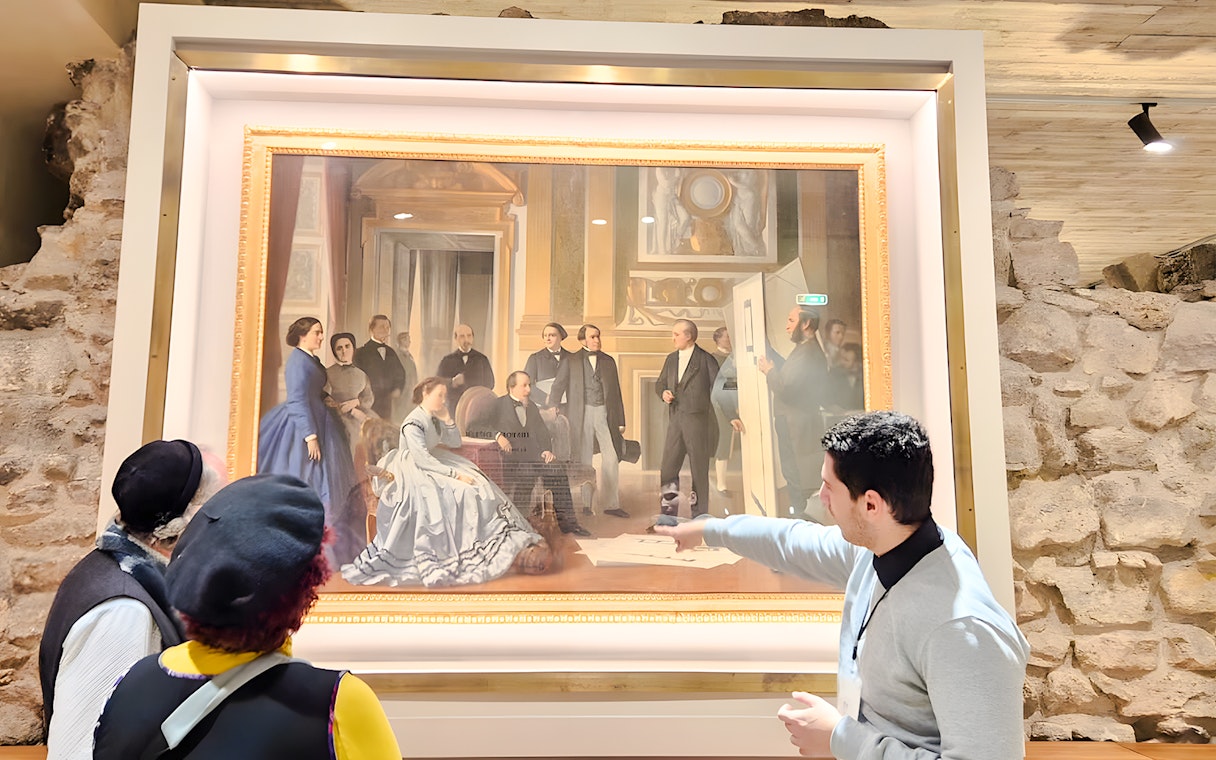 Visitors viewing a painting inside the Louvre Museum, Paris, France.