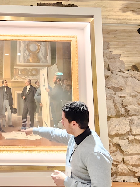 Visitors viewing a painting inside the Louvre Museum, Paris, France.