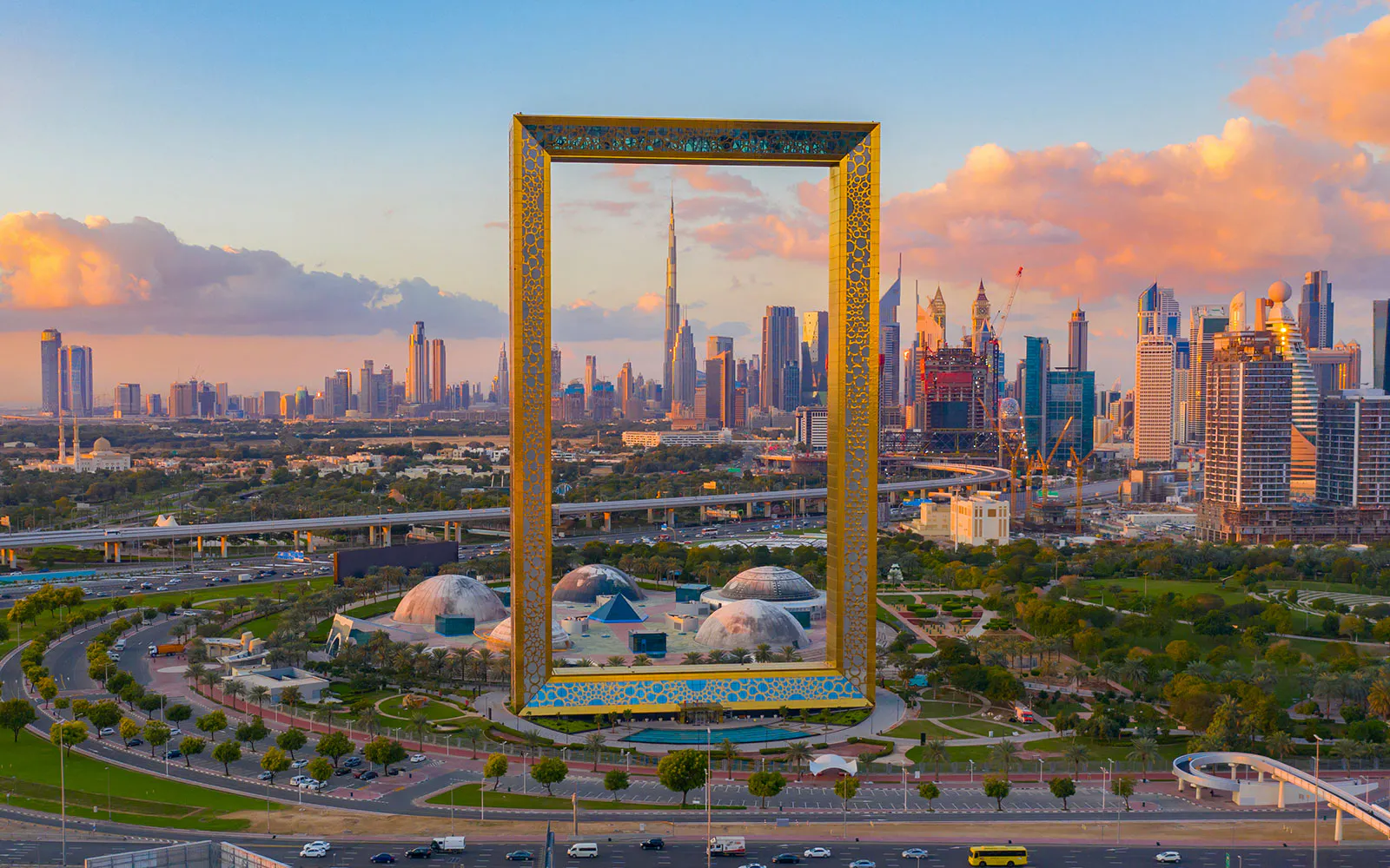 Dubai Frame rises above Zabeel Park with the Dubai skyline visible through its centre.