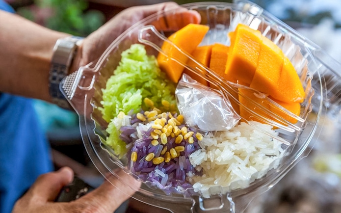 Mango sticky rice with colorful rice varieties and coconut sauce, traditional Thai dessert.