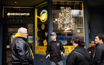 Chef guiding a group outside Hashtag Waffles during Pike Place Market food tour.