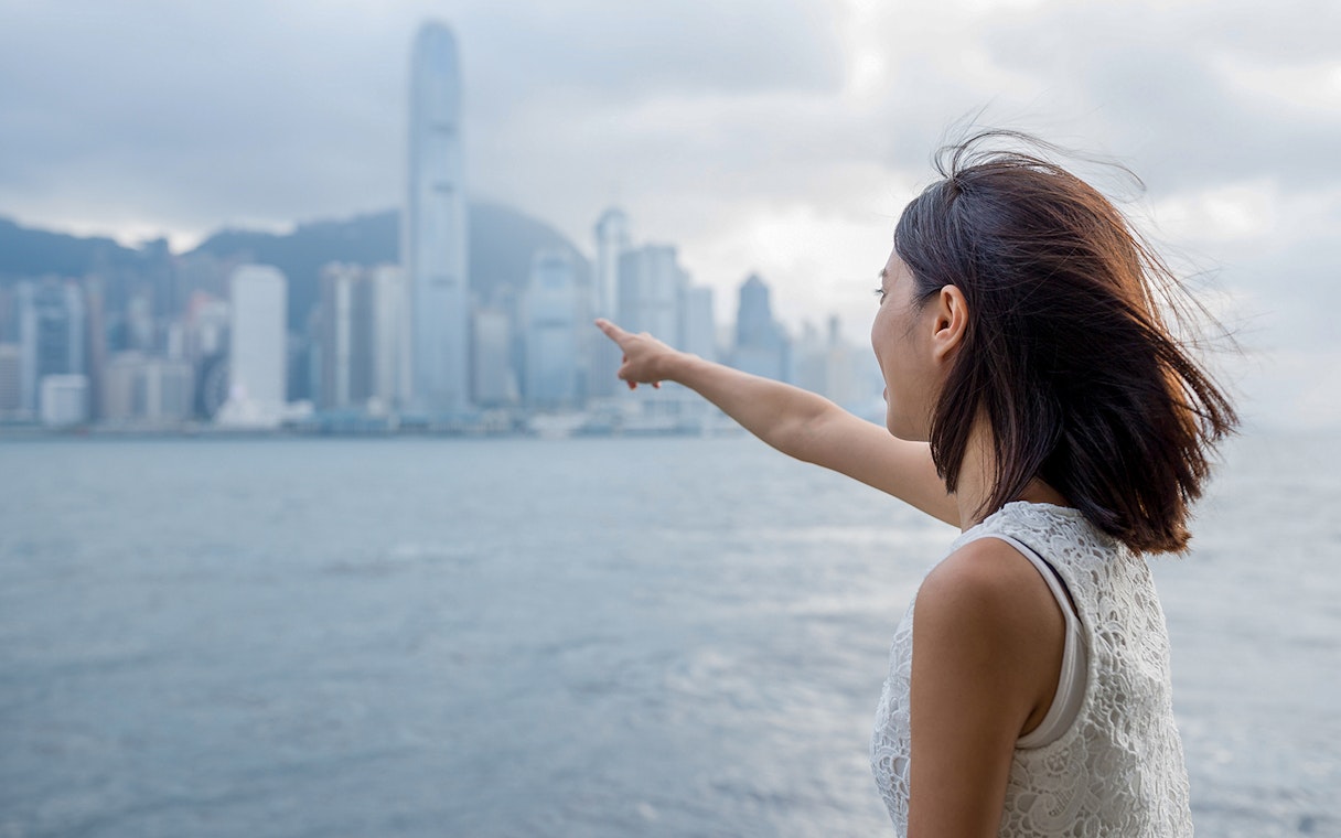 Person pointing towards Hong Kong skyline from ferry, Cotai Ferry Transfers.