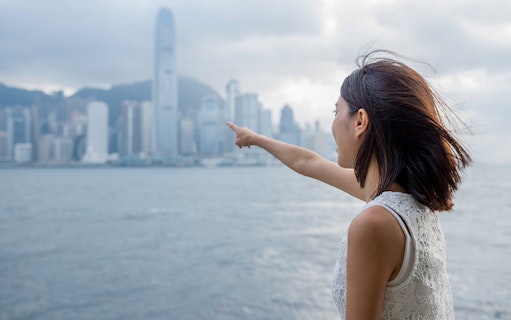 Person pointing towards Hong Kong skyline from ferry, Cotai Ferry Transfers.