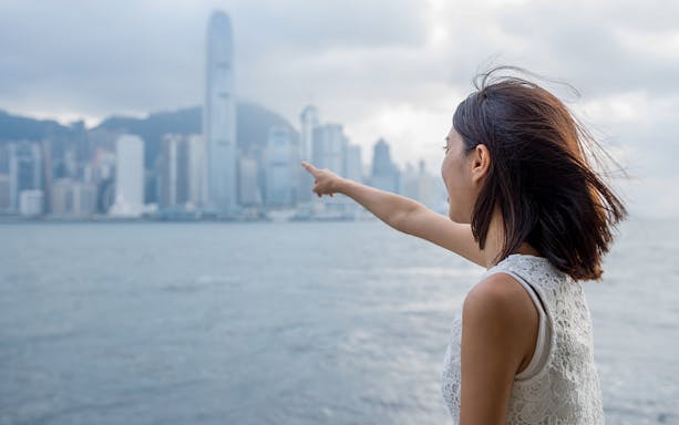 Person pointing towards Hong Kong skyline from ferry, Cotai Ferry Transfers.
