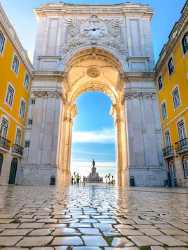 Rua Augusta Arch in Lisbon with cobblestone street and distant statue view.