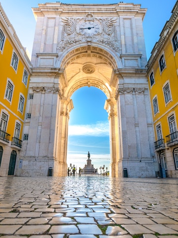 Rua Augusta Arch in Lisbon with cobblestone street and distant statue view.