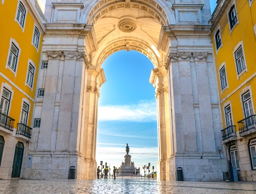Rua Augusta Arch in Lisbon with cobblestone street and distant statue view.