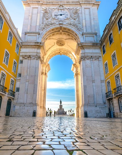 Rua Augusta Arch in Lisbon with tourists walking beneath the ornate stone structure.
