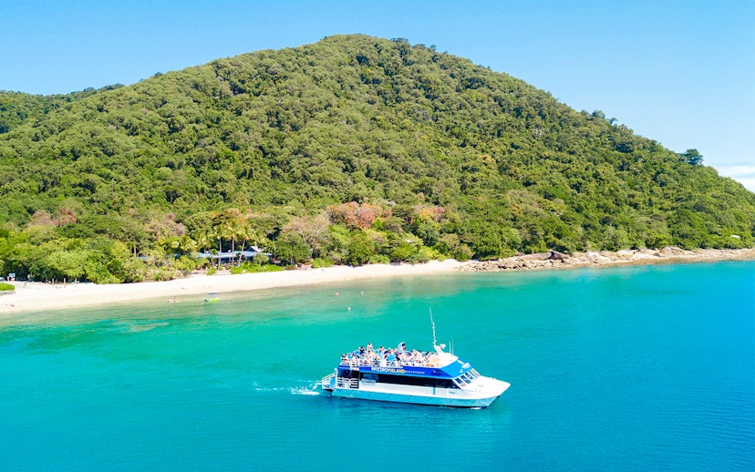 Cruise ship approaching Fitzroy Island beach with lush green hills in the background.