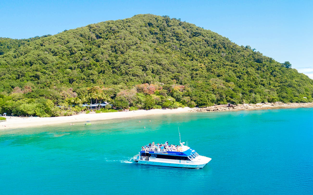 Cruise ship approaching Fitzroy Island beach with lush green hills in the background.
