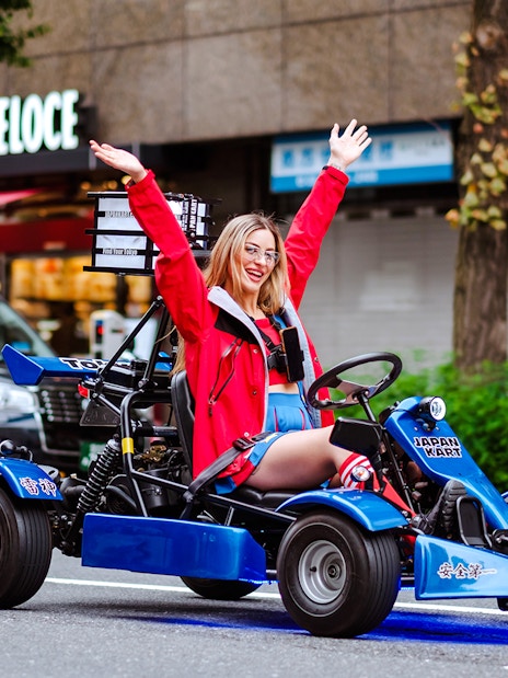 Woman enjoying go-kart ride in Shibuya during Tokyo Tower tour.