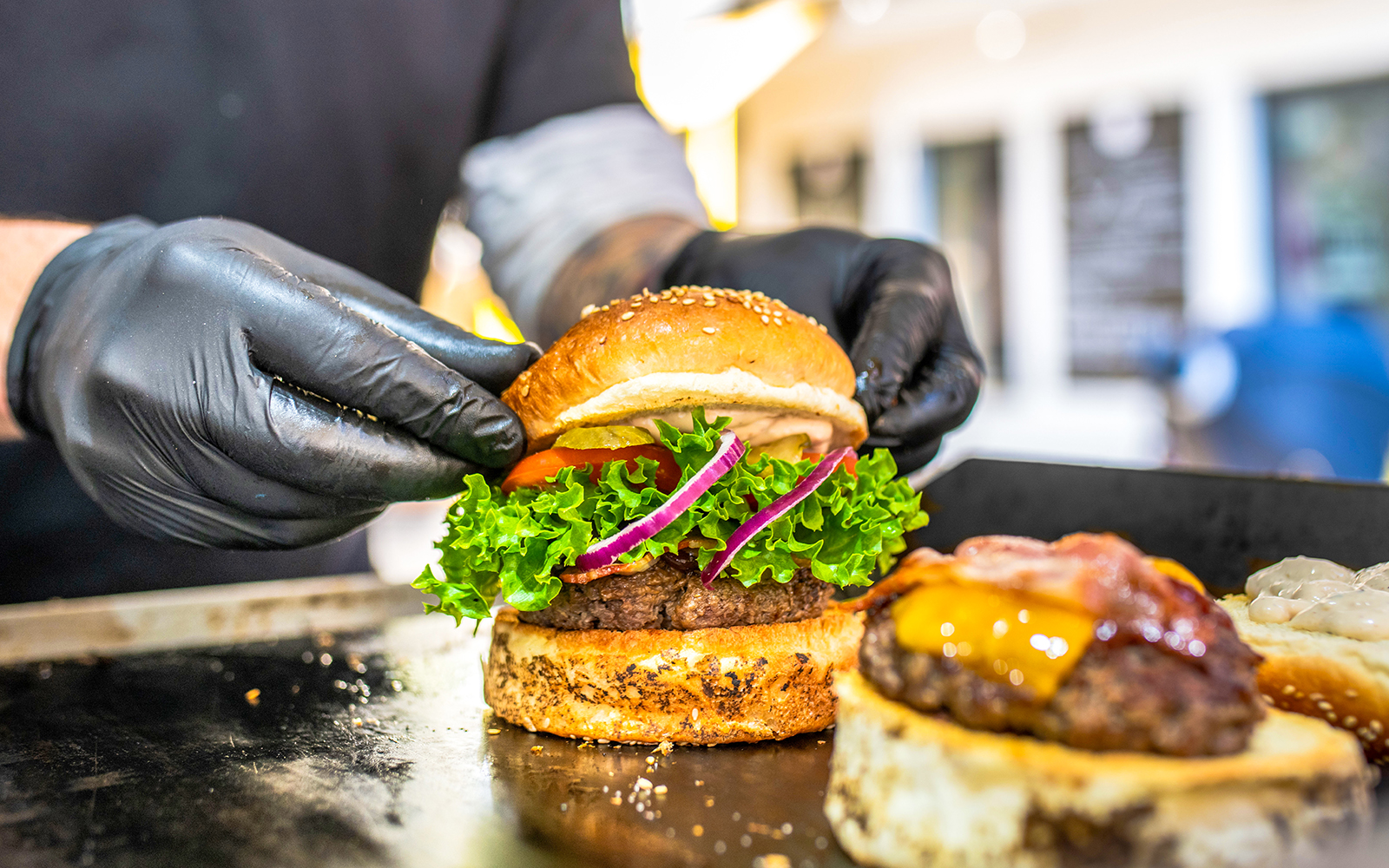 Iemand die een verse hamburger klaarmaakt op de grill