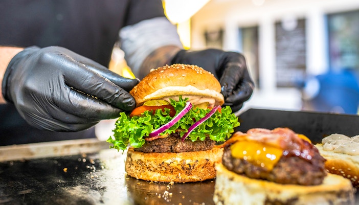 Une personne préparant un hamburger frais sur un gril