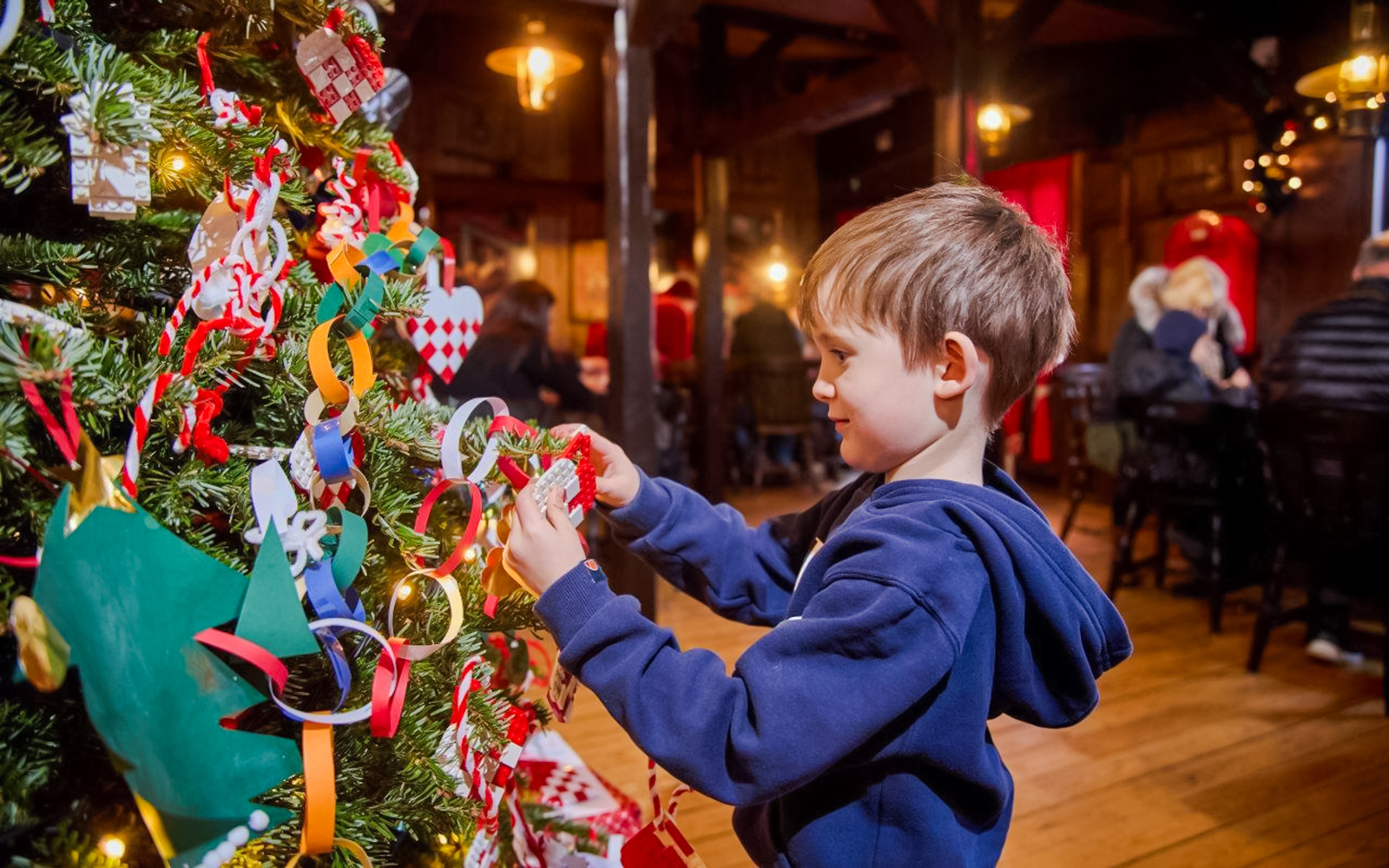 Child decorating a Christmas tree with LEGO ornaments at LEGOLAND® Billund.
