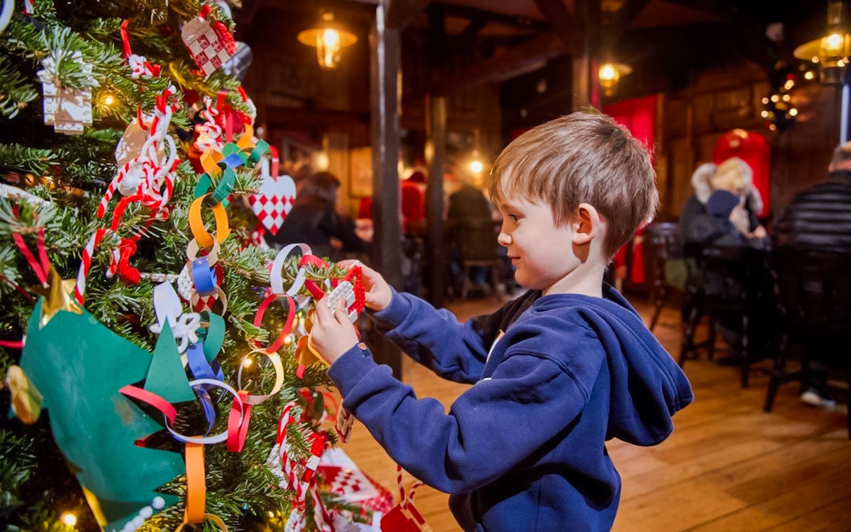 Child decorating a Christmas tree with LEGO ornaments at LEGOLAND® Billund.