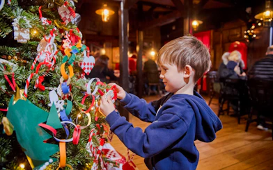 Child decorating a Christmas tree with LEGO ornaments at LEGOLAND® Billund.