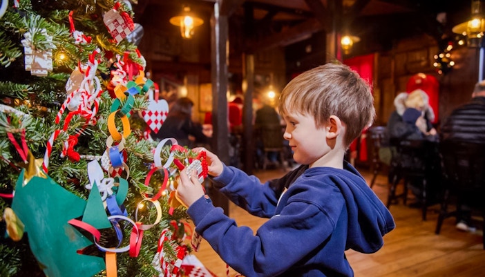 Child decorating a Christmas tree with LEGO ornaments at LEGOLAND® Billund.