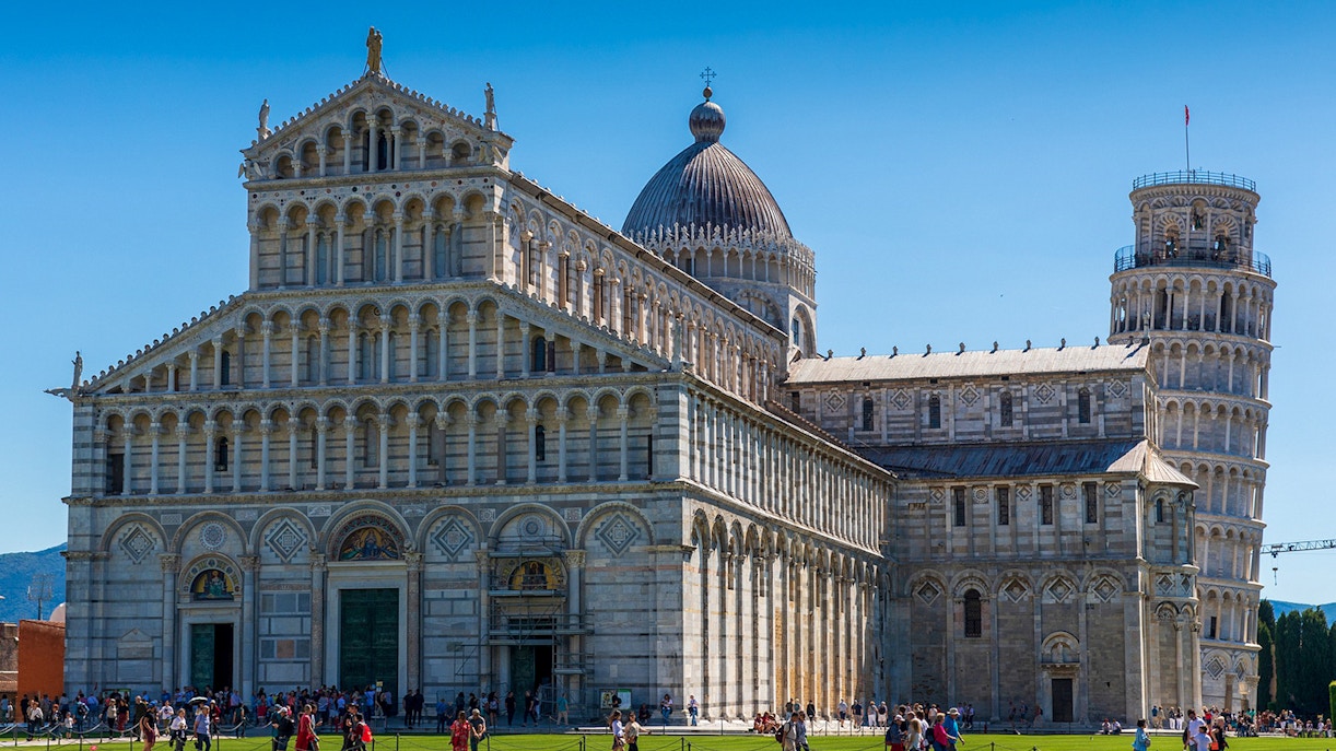 Leaning Tower of Pisa in Piazza dei Miracoli, Pisa, with tourists exploring the historic site.