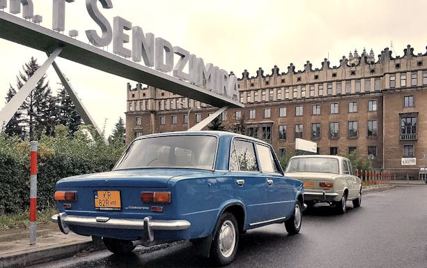 Retro cars parked in front of Nowa Huta's Sendzimir Steelworks entrance in Kraków.