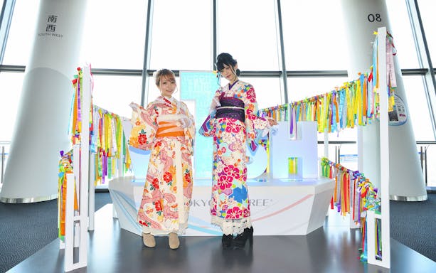 Two people in colorful kimonos at Tokyo Skytree observation deck.