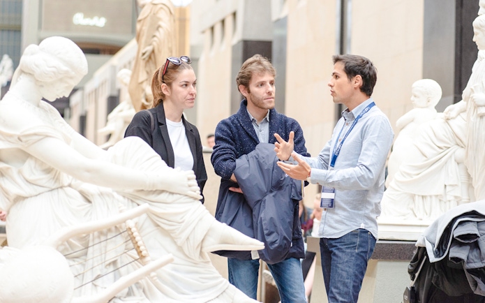 Guide explaining sculptures to tourists inside Orsay Museum, France.