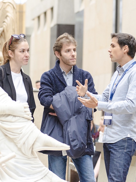 Guide explaining sculptures to tourists inside Orsay Museum, France.