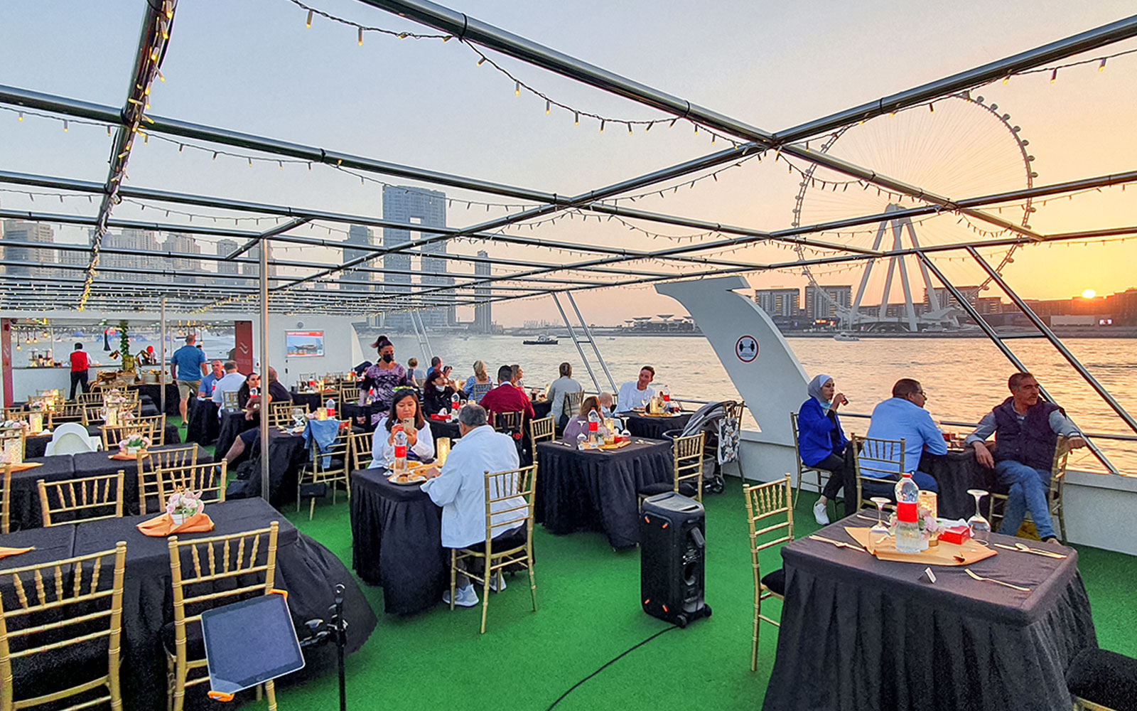 Guests dining on a sunset cruise in Dubai Marina with views of the Ferris wheel.