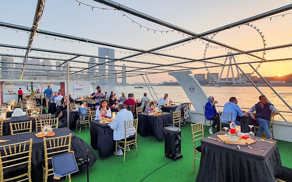 Guests dining on a sunset cruise in Dubai Marina with views of the Ferris wheel.