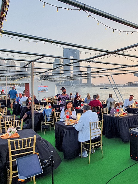 Guests dining on a sunset cruise in Dubai Marina with views of the Ferris wheel.
