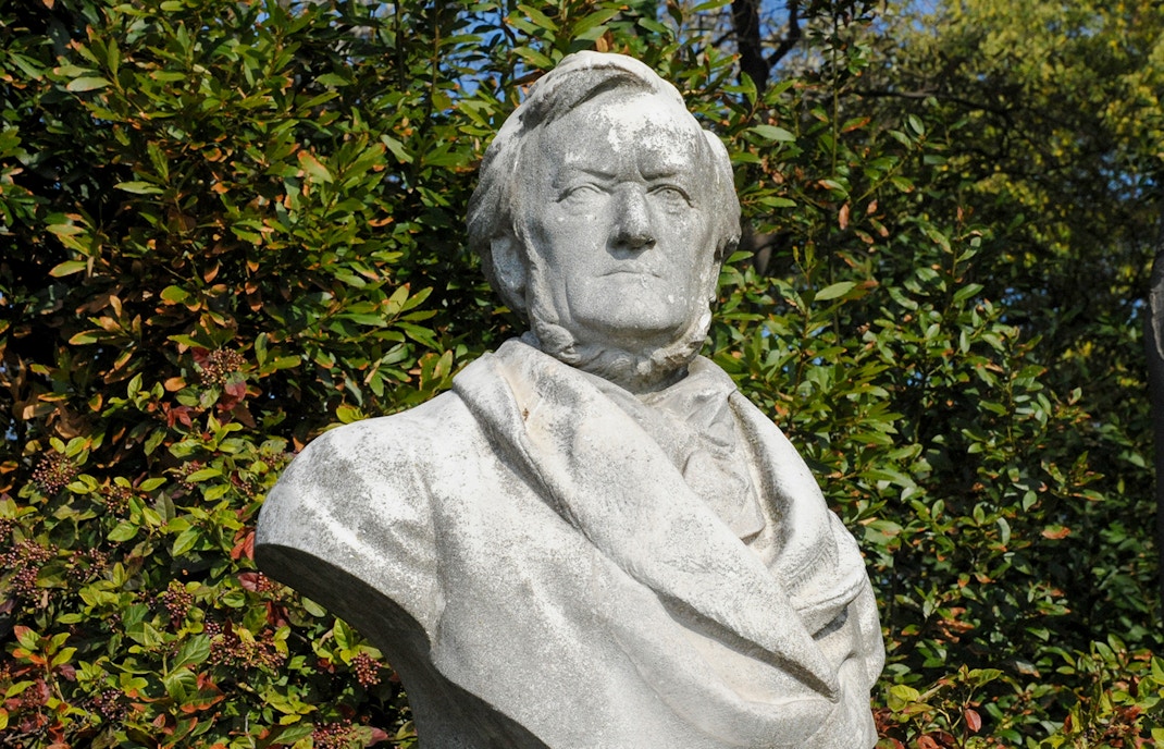 Richard Wagner statue in Leipzig, Germany, surrounded by trees and historic architecture.