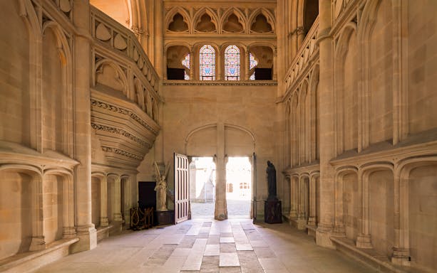 Interior view of Castle of Pierrefonds with stone arches and stained glass windows.