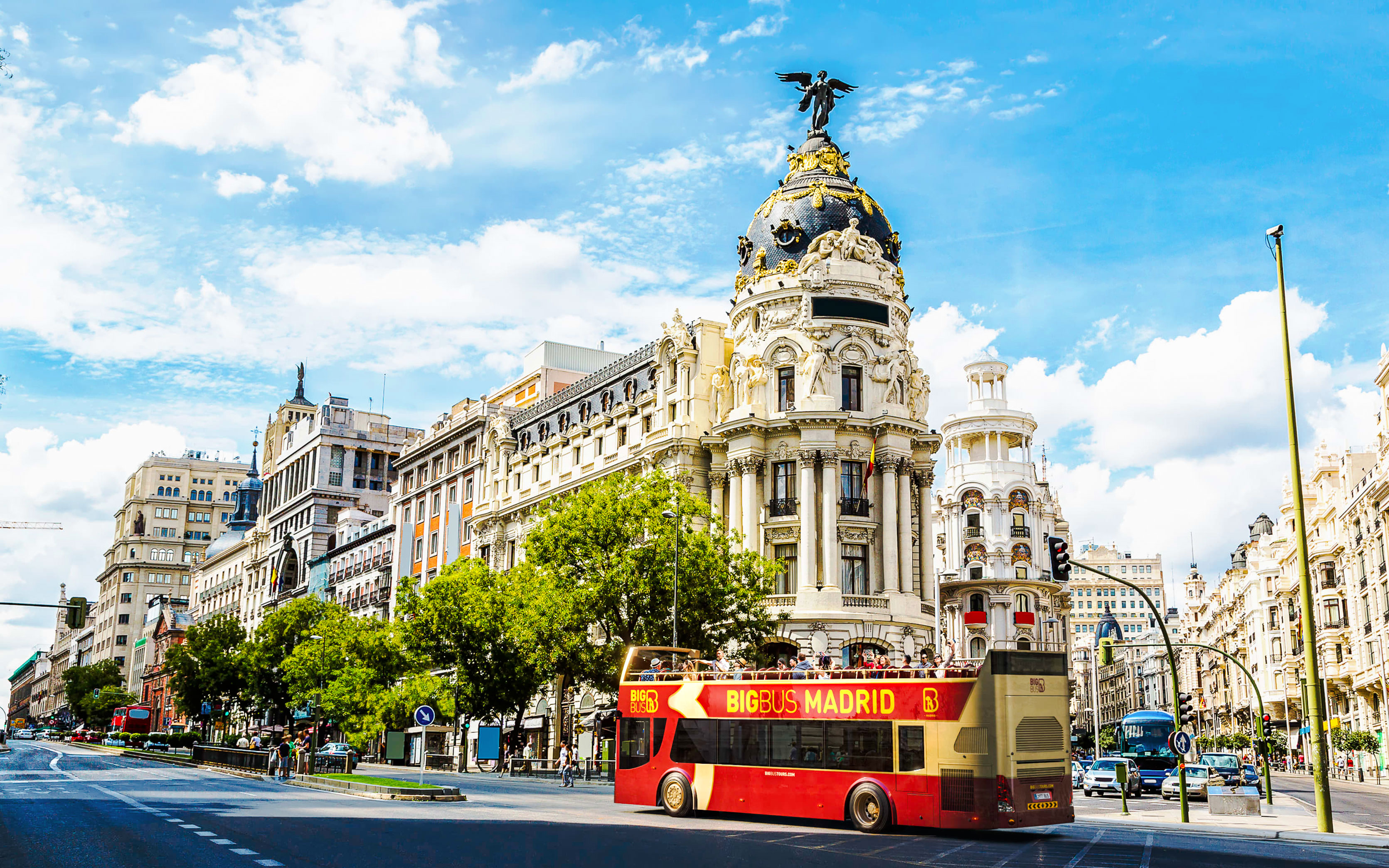 Big Bus Madrid passing by the Metropolis Building on a sunny day.