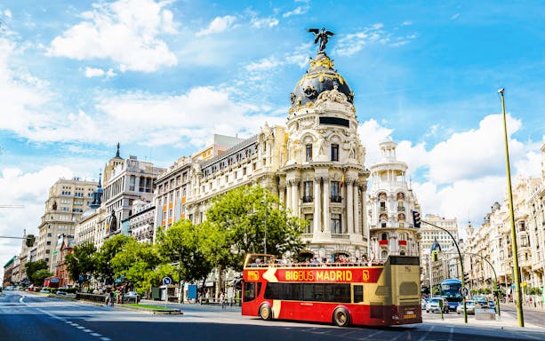 Big Bus Madrid passing by the Metropolis Building on a sunny day.