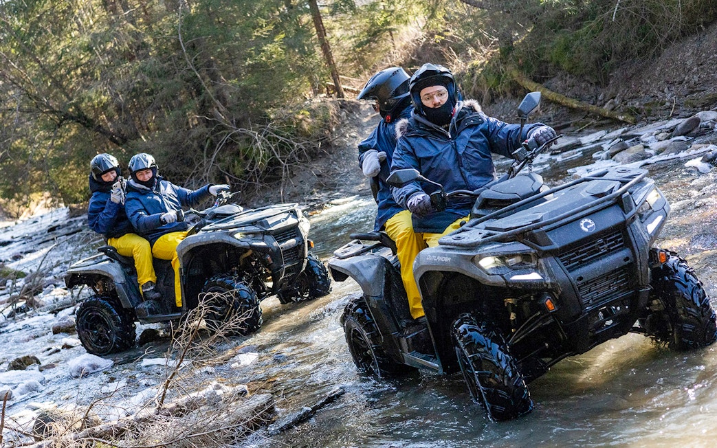Guests quad biking through a forest stream in Zakopane.