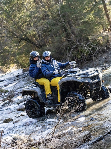 Guests quad biking through a forest stream in Zakopane.