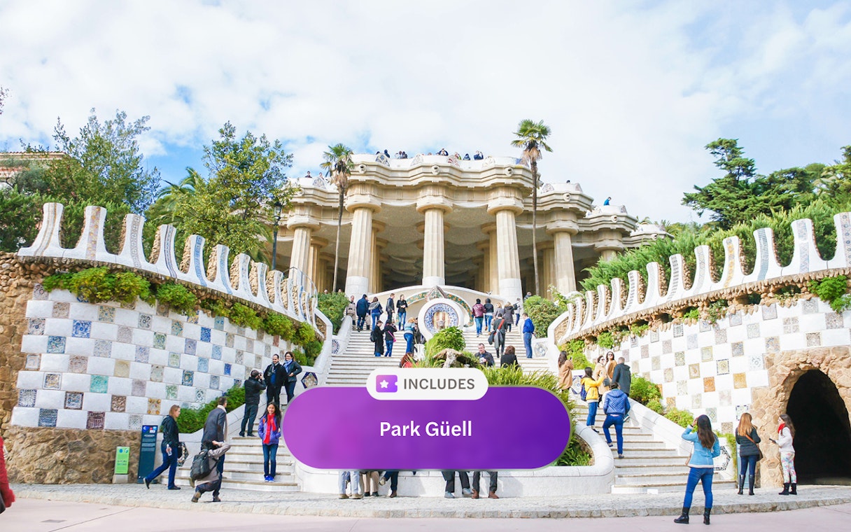 Visitors at Park Güell entrance with mosaic tiles and columns, Barcelona.