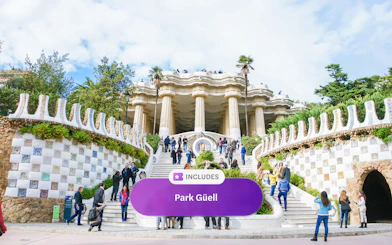 Visitors at Park Güell entrance with mosaic tiles and columns, Barcelona.