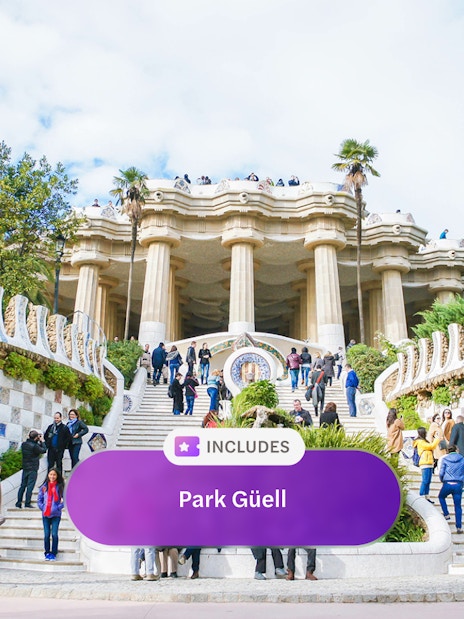 Visitors at Park Güell entrance with mosaic tiles and columns, Barcelona.
