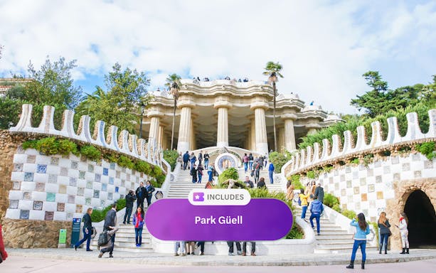 Visitors at Park Güell entrance with mosaic tiles and columns, Barcelona.