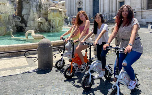Visitors on e-bikes near a historic fountain in Rome, Italy, for Circus Maximus virtual reality tour.