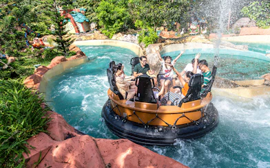 Guests on a water ride at VinWonders, surrounded by lush greenery and themed structures.