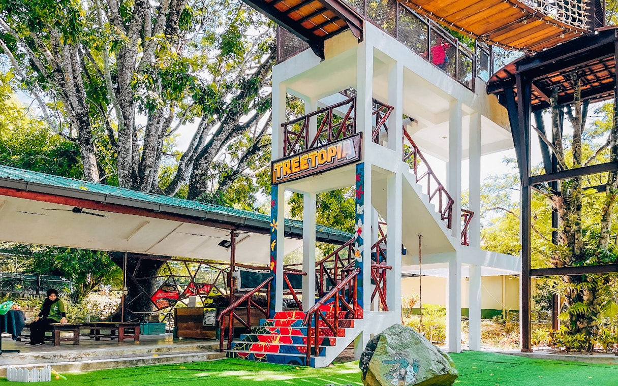 Treetop adventure area at Crocodile Adventureland Langkawi with colorful stairs and greenery.