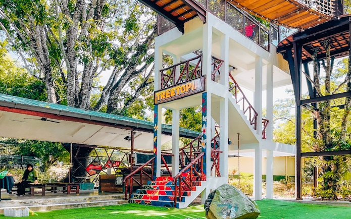 Treetop adventure area at Crocodile Adventureland Langkawi with colorful stairs and greenery.