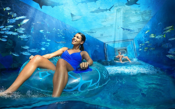 Visitors enjoying a water ride surrounded by marine life at Aquaventure, Atlantis Dubai.