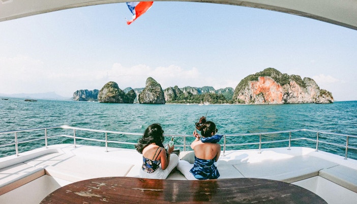 Tourists on a yacht enjoying views of limestone cliffs in Phang Nga Bay, Phuket.