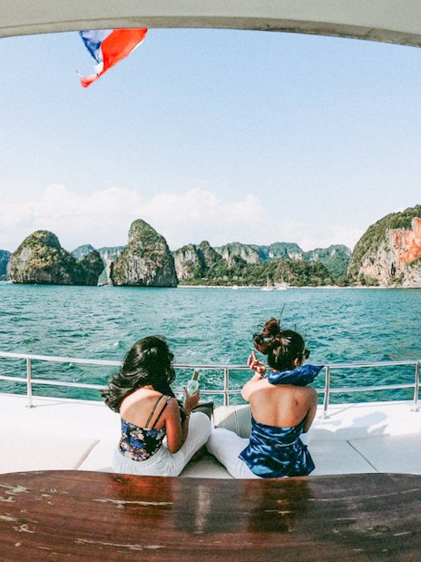 Tourists on a yacht enjoying views of limestone cliffs in Phang Nga Bay, Phuket.